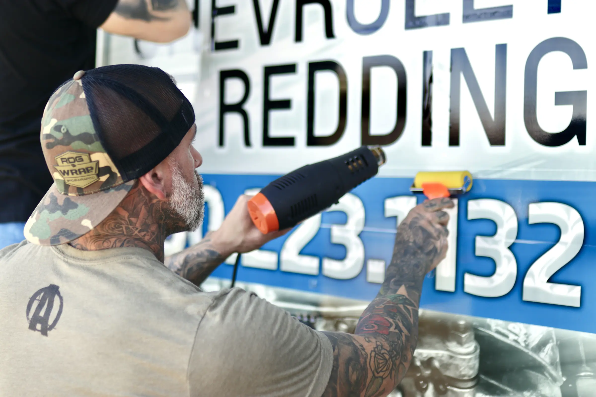 Installer heat-applying Chevrolet of Redding lettering during a wrap