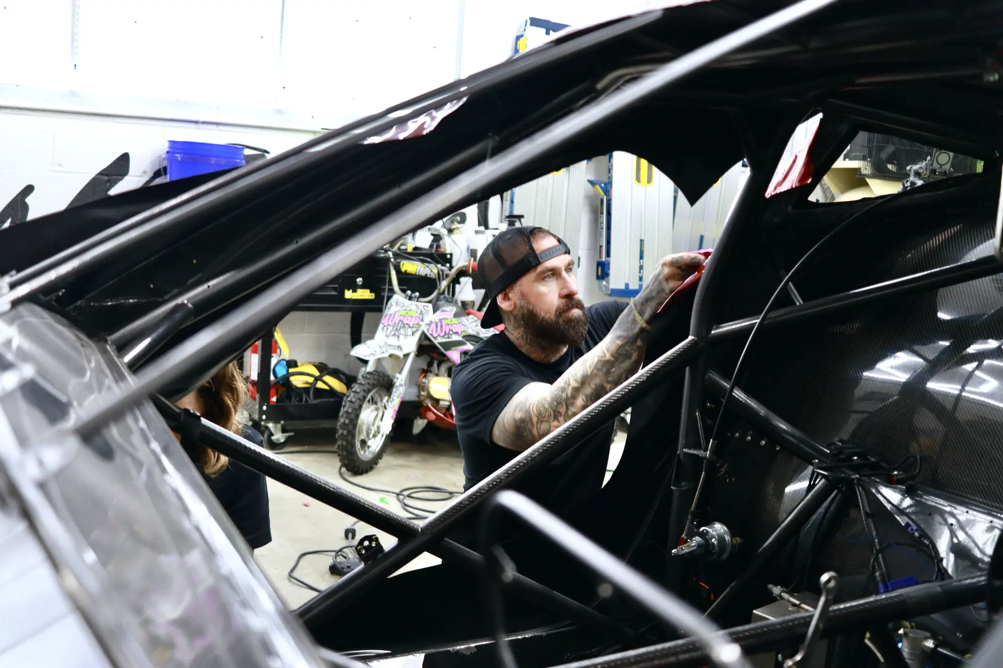 Wrap installer working inside a race car cage at a competition