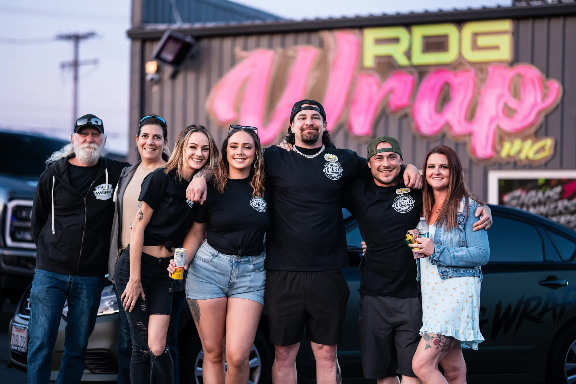 Friends and fellow business owners in front of the shop's neon RDG Wrap sign
